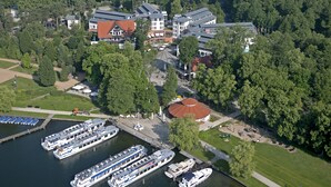 A riverside hotel with multiple boats docked, surrounded by lush greenery and a mix of modern and traditional architecture.