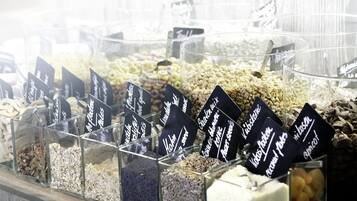 A variety of grains and seeds displayed in clear containers with labels, likely in a store or market setting.