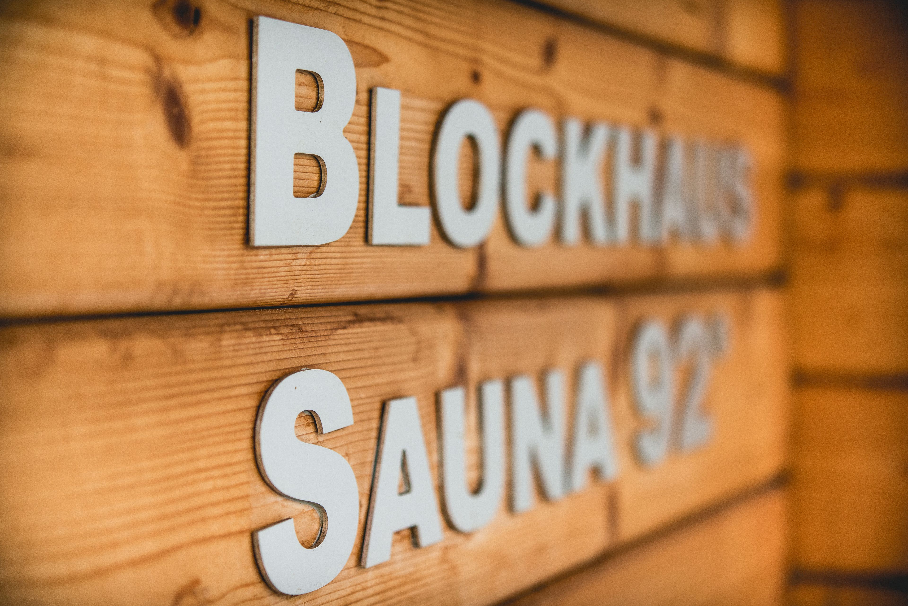 A wooden sign with the words "BLOCKHAUS" and "SAUNA 92" indicating a sauna facility.