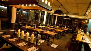 A restaurant with multiple tables set for dining, candles on each table, and a warm, inviting atmosphere.