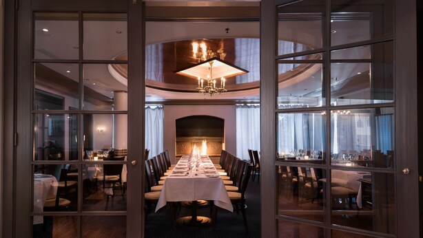 A formal dining room with a long table set for a meal, surrounded by chairs, and a chandelier above. - Radisson Blu Park Hotel, Oslo (Bærum)