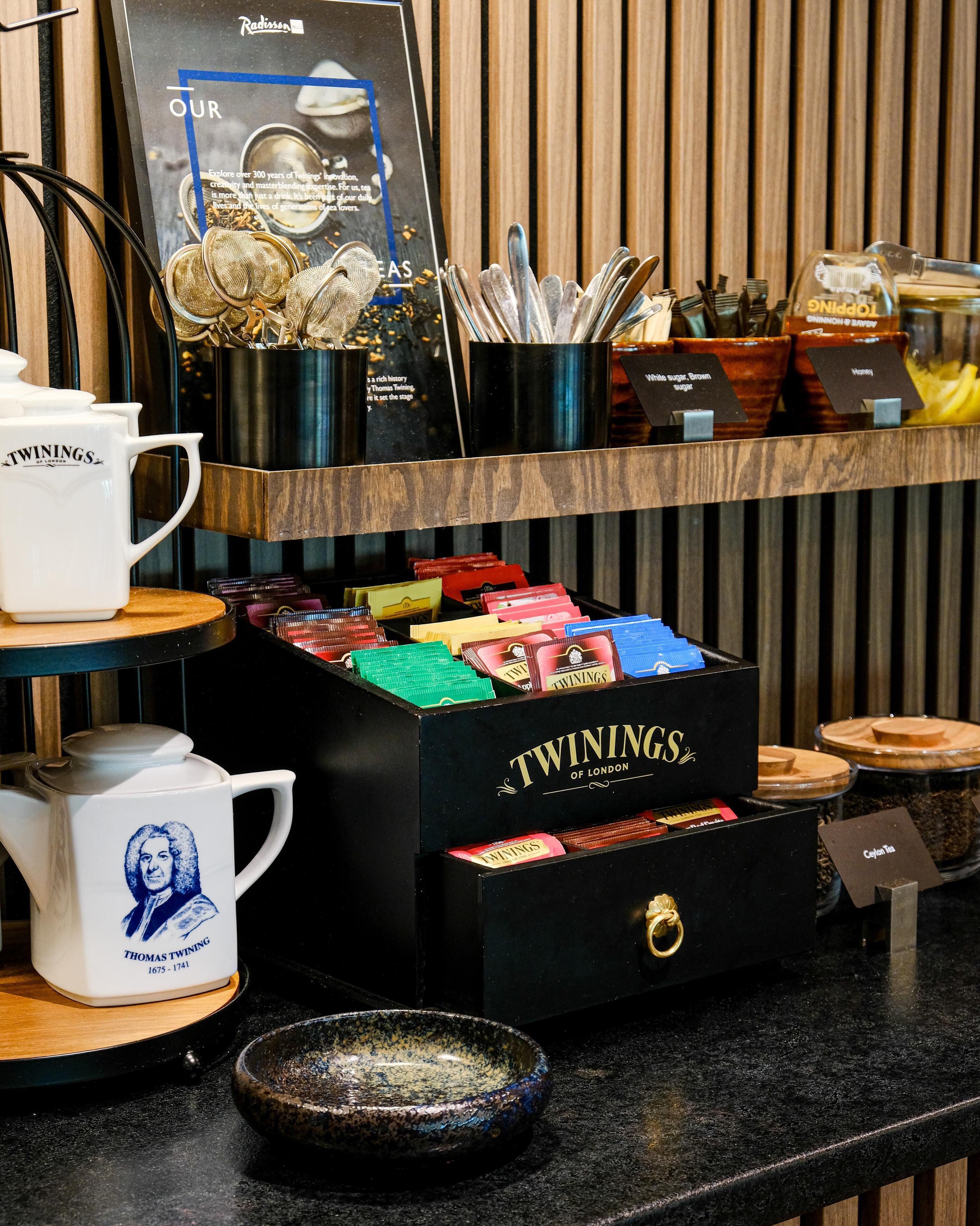 Estación de té con cajas de té Twinings, una tetera y un cartel.