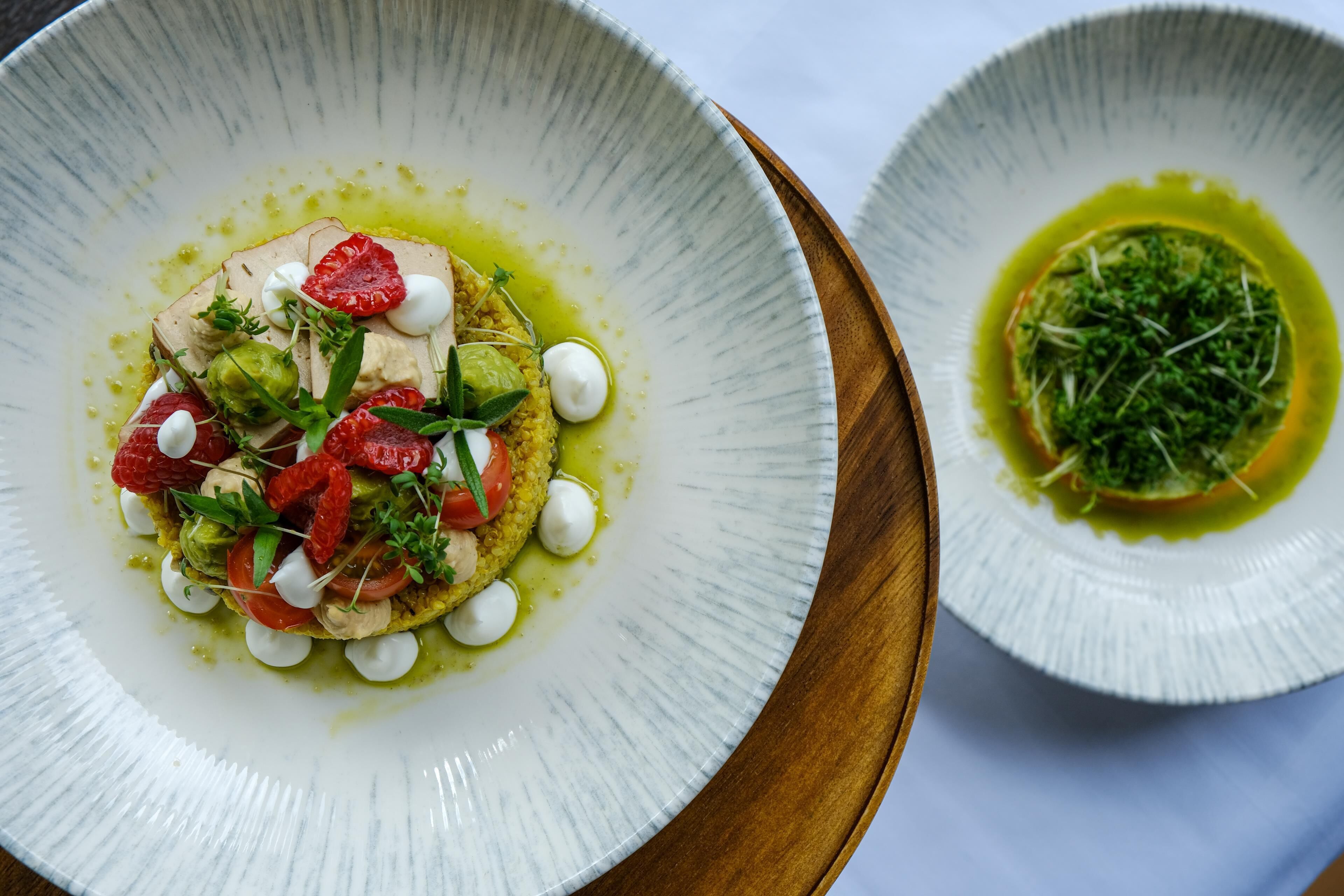 Two white ceramic plates with food, one with a wooden board.