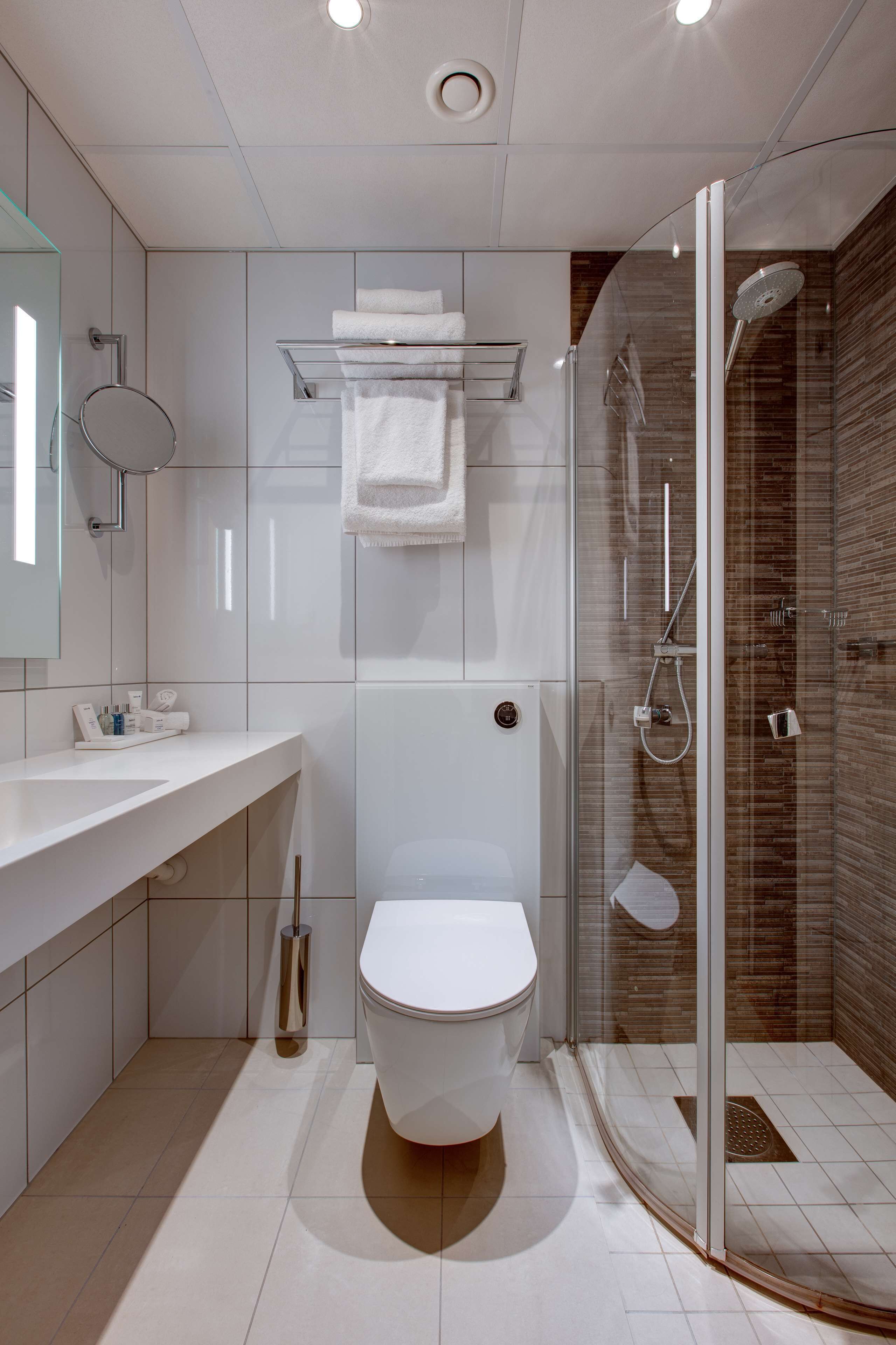 A modern bathroom with a toilet, sink, and glass-enclosed shower.