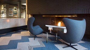 A modern lounge area with two contemporary chairs, a fireplace, and a marble reception desk. - Radisson Blu Park Hotel, Oslo (Bærum)