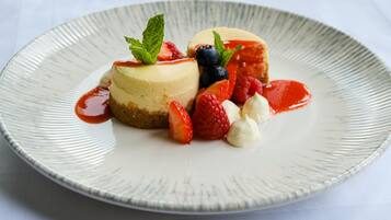 A dessert plate with a cheesecake, strawberries, raspberries, and a mint garnish.