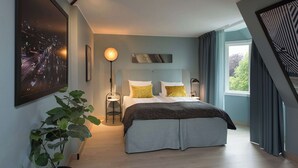 Un dormitorio moderno con cama, mesitas de noche y un ventanal grande.