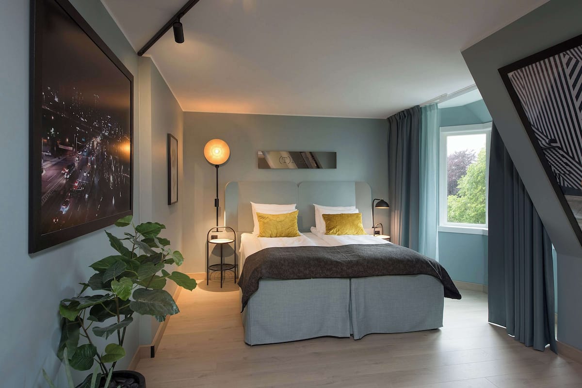 Ein modernes Schlafzimmer mit einem Bett, Nachttischen und einem großen Fenster.
