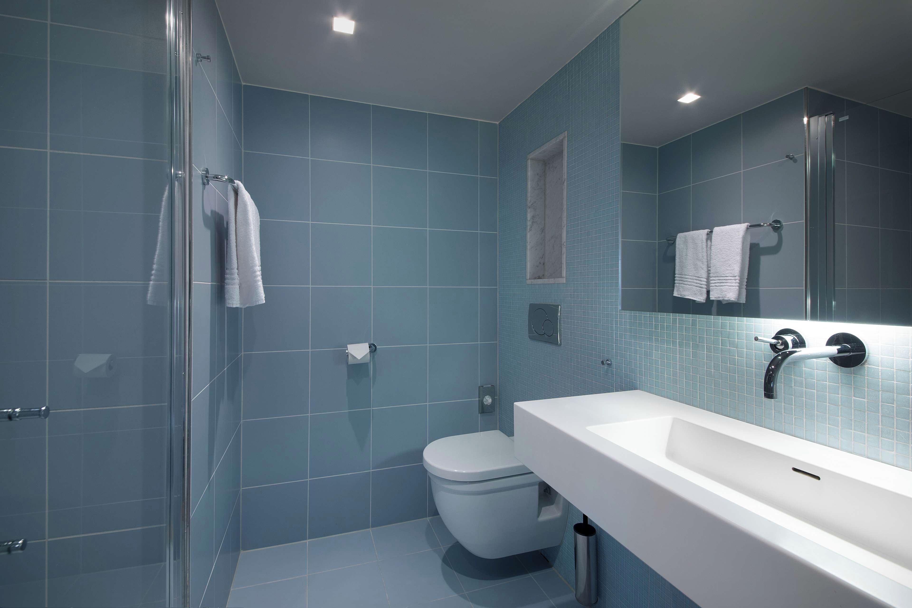 A bathroom with a glass shower enclosure, a white sink, and a toilet.