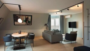 Una sala de estar moderna con una mesa redonda, un sofá gris y sillones negros.