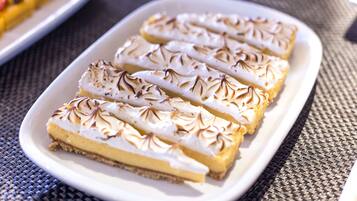 A white rectangular plate with four slices of a layered dessert, possibly a pie or tart, on a woven tablecloth.