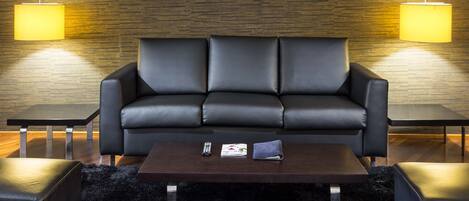 A modern living room with a black leather sofa, two side tables, and a coffee table.