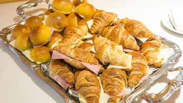Un plateau contenant un assortiment de viennoiseries, notamment des croissants et des petits pains, disposés sur un élégant plateau en argent.