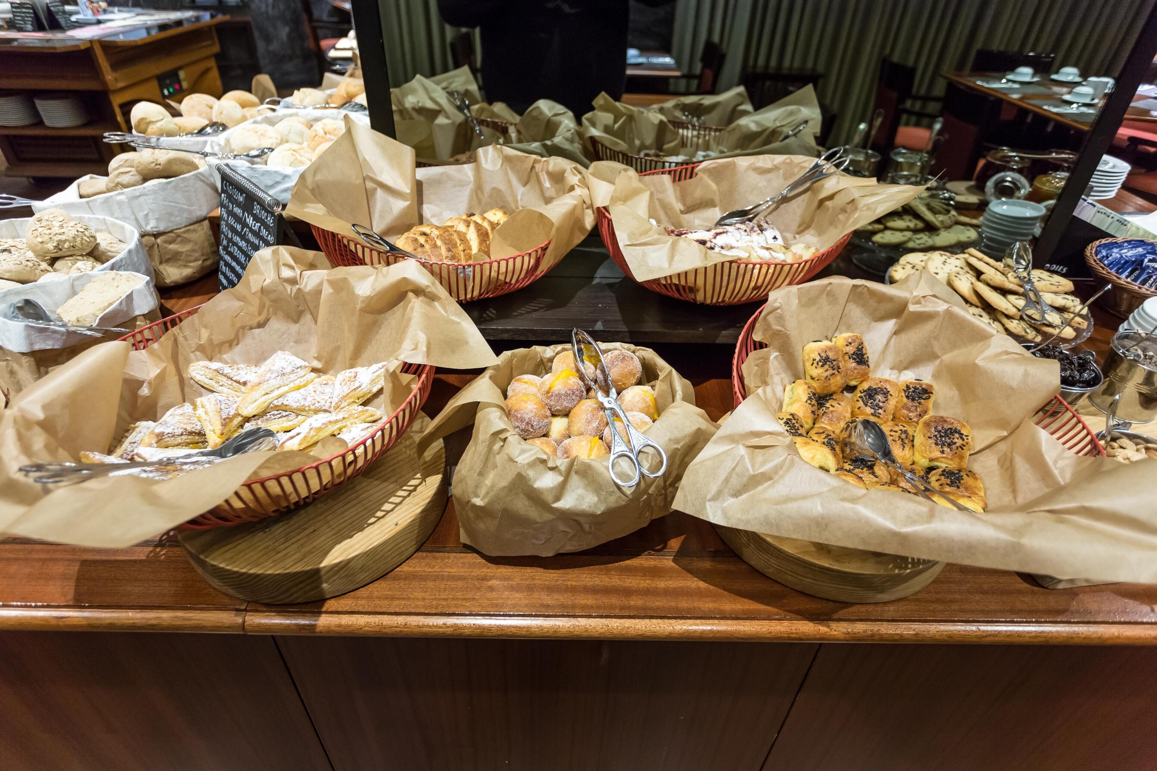 A buffet with various baked goods and pastries in baskets.