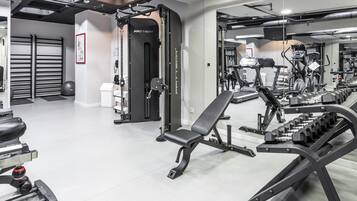 Un gimnasio moderno con varios equipos de ejercicio, como una prensa de banca, estantes para pesas y máquinas de cardio.