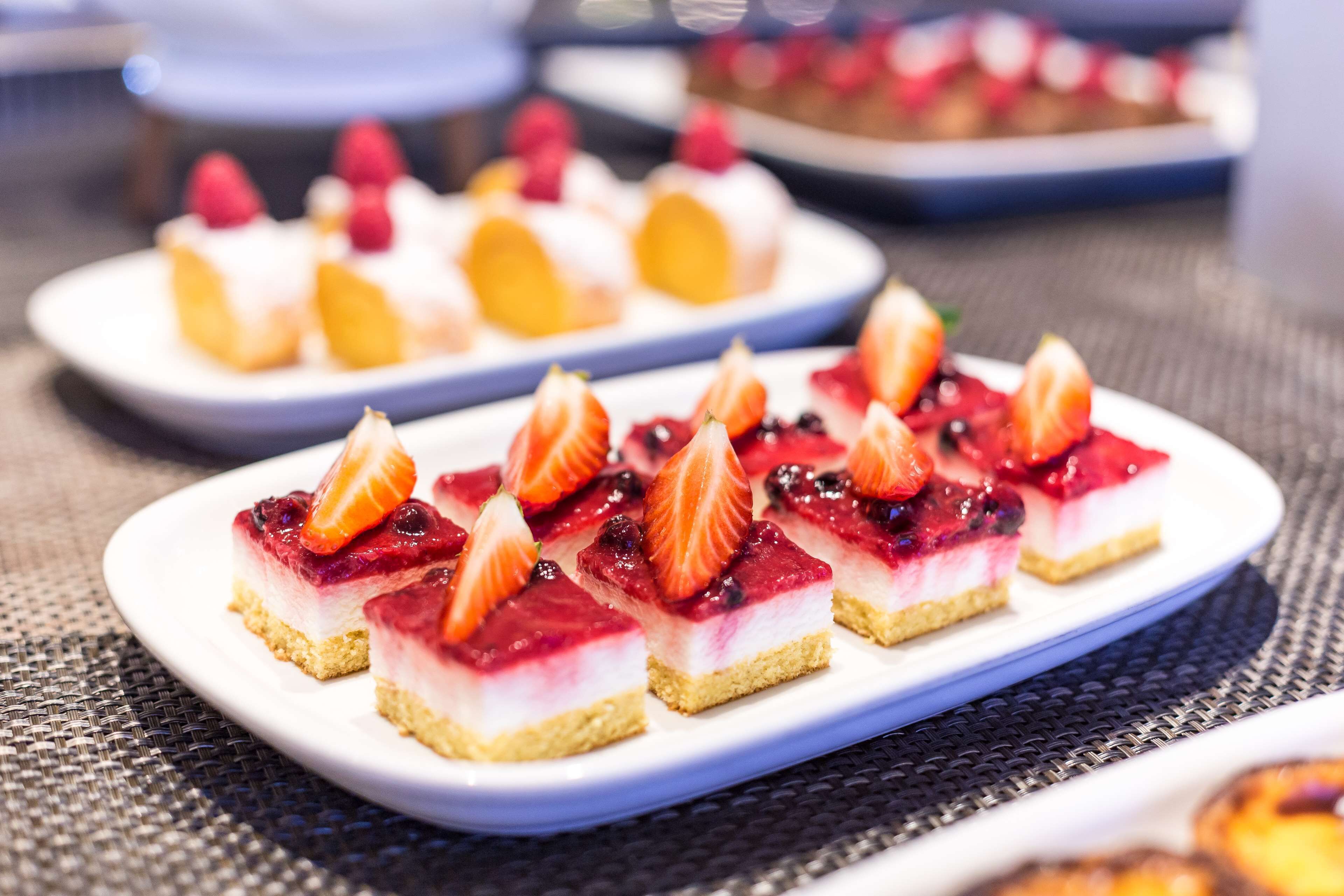 Un plato con una bandeja de postres, varios coronados con fruta.