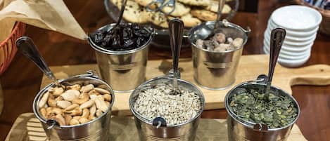 Una mesa con recipientes metálicos que contienen diversas nueces y semillas.