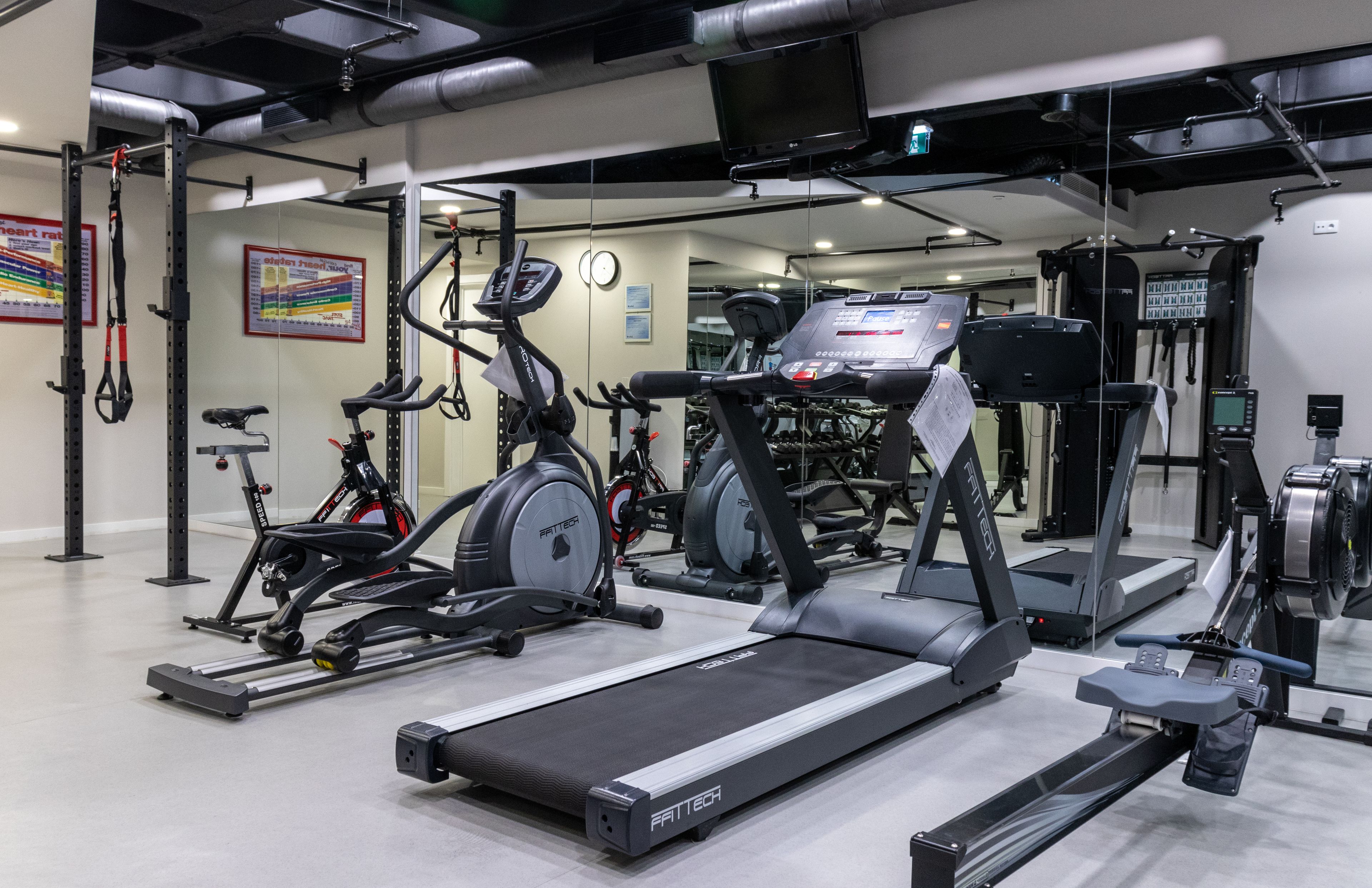 Un gimnasio con cintas de correr, bicicletas estáticas y máquinas de pesas.