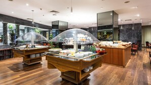Un vestíbulo de hotel moderno con zona de buffet, suelo de mármol y grandes espejos.