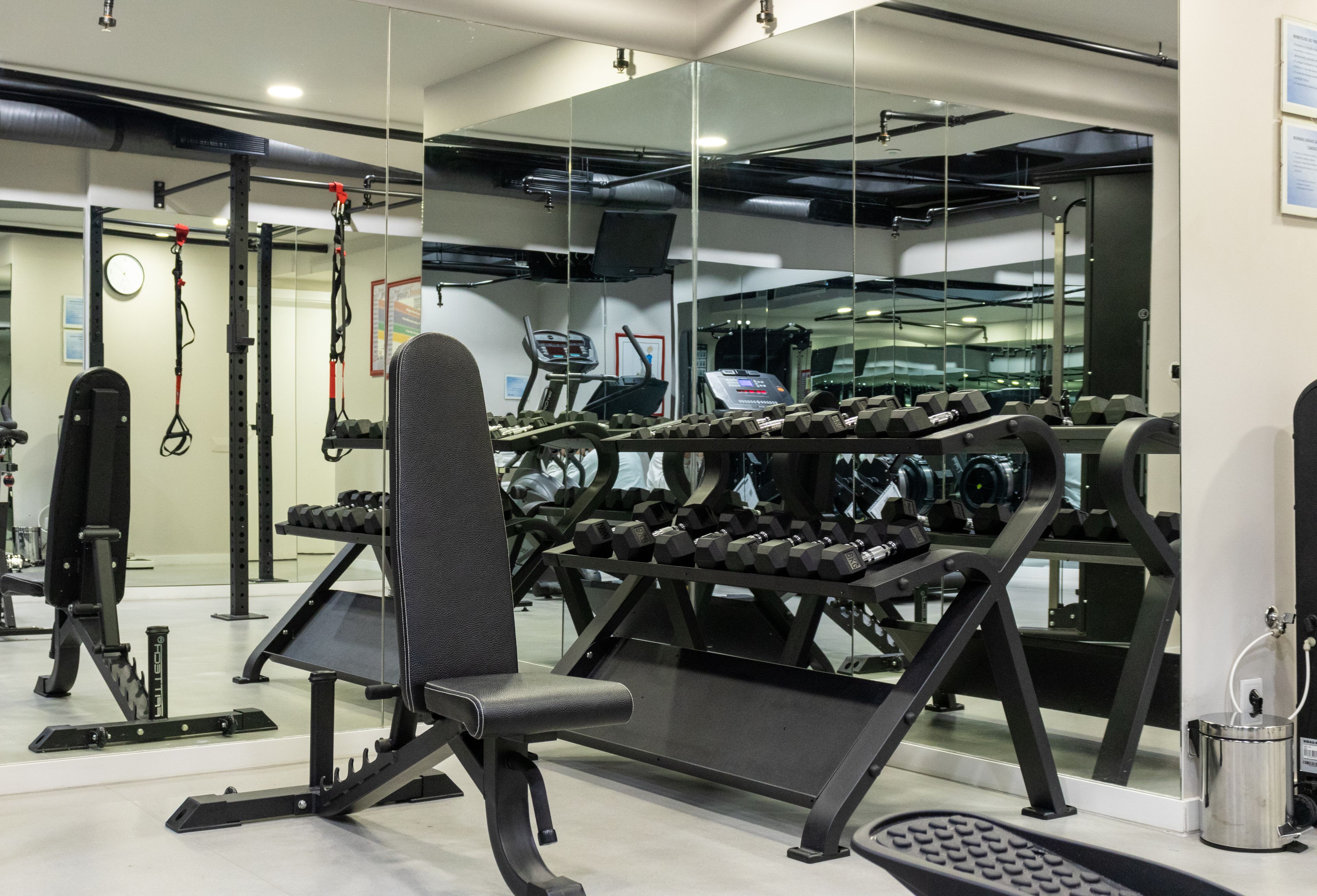 Ein Fitnessstudio mit Trainingsgeräten, einem Spiegel und einem Laufband.