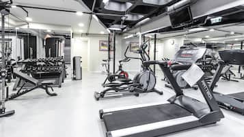 Un gimnasio con cintas de correr, mancuernas y máquinas de pesas.