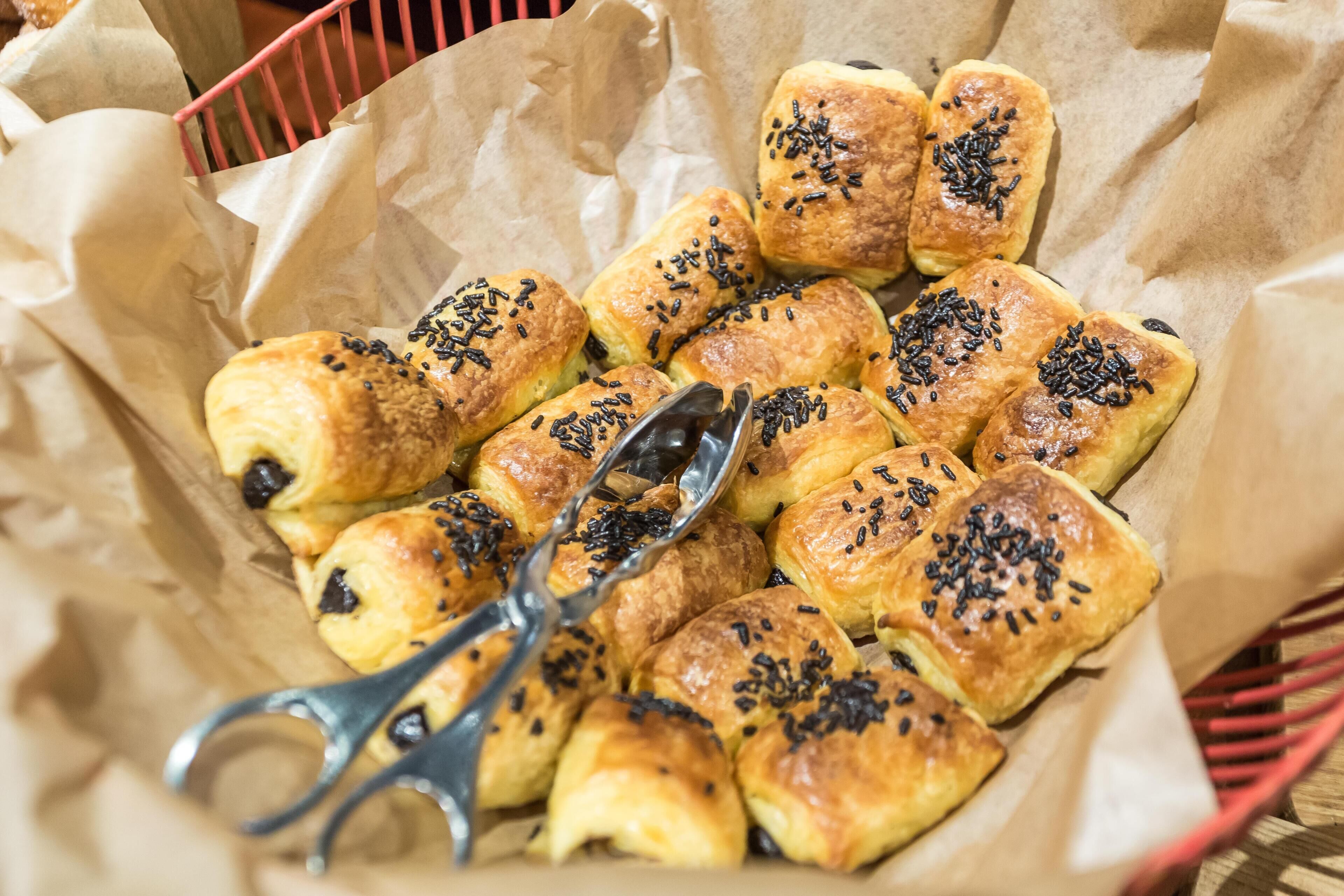 A basket of pastries with black sesame seeds on a paper-lined tray.