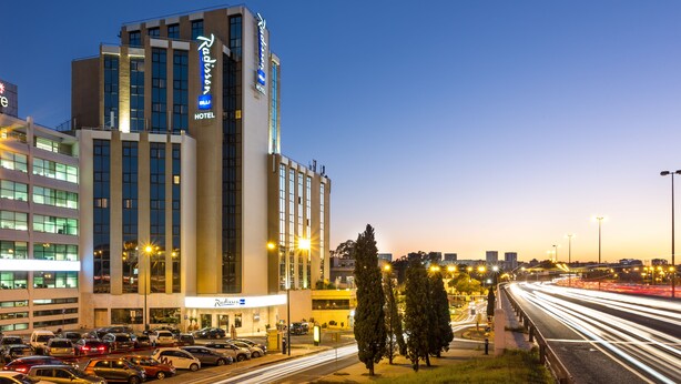 Un hotel Radisson con un diseño moderno, destacando un letrero llamativo y varios pisos.