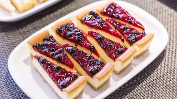 Un plato blanco con rebanadas de tarta de queso coronadas con compota de arándanos.