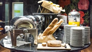 A breakfast buffet with a bread slicer, a juicer, and stacked plates.
