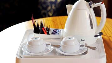 A white tray with two teacups and a teapot labeled "LovA" on a wooden table.