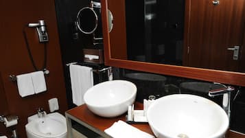 Un baño moderno con dos lavamanos grandes de color blanco, un bidé, un espejo y un perchero para toallas.