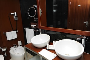 A modern bathroom with two large white sinks, a bidet, a mirror, and a towel rack. - Radisson Blu Hotel (Lisbon)