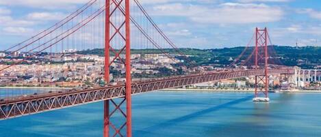 Uma grande ponte vermelha sobre a água, com um horizonte urbano ao fundo.