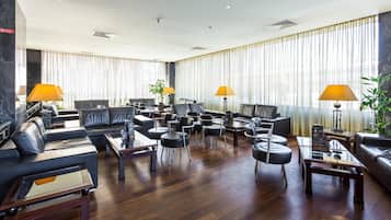 A spacious lobby with leather sofas, round tables, and lamps.