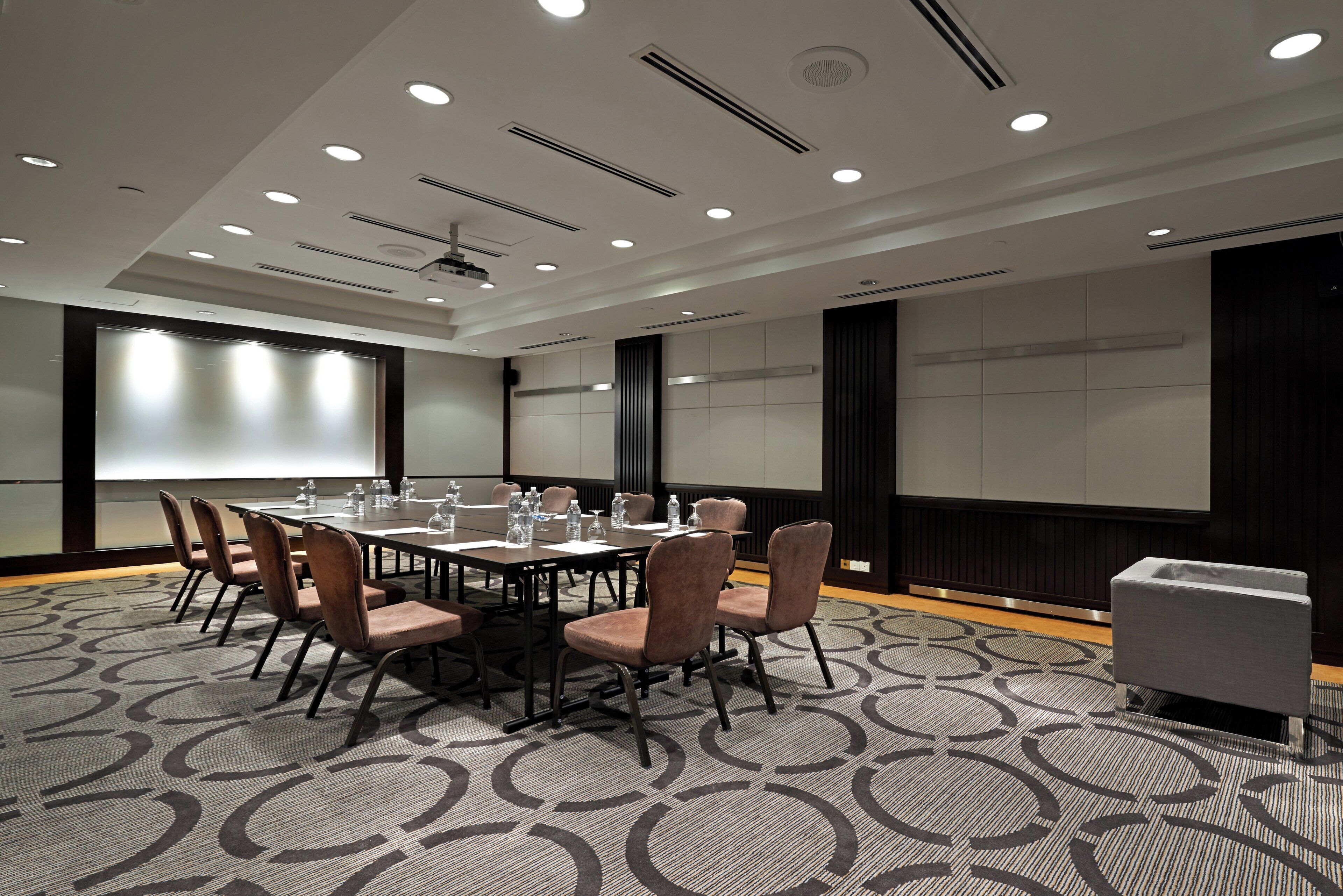 A conference room with a large table, chairs, and a projector screen.