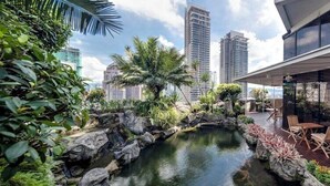 A rooftop garden with a water feature, seating area, and city skyline views.
