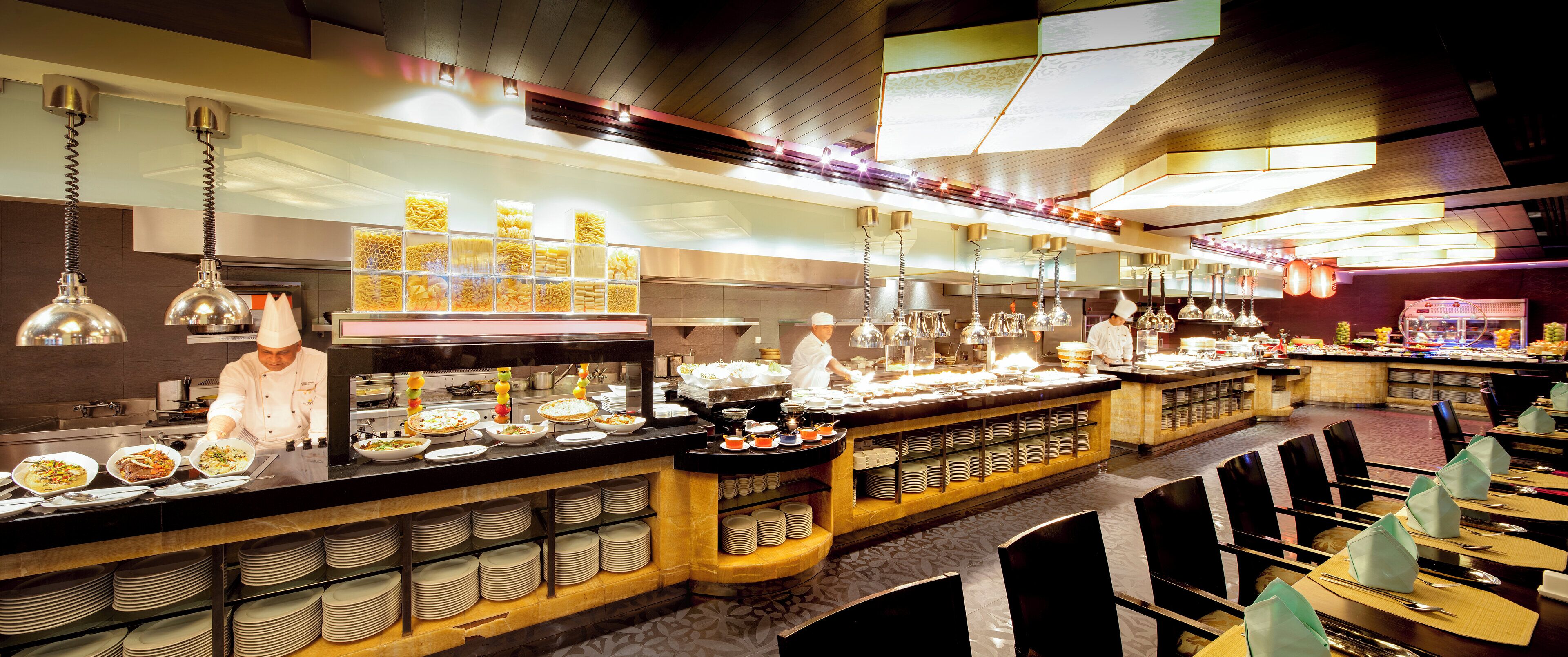 A buffet setup with multiple food stations and a chef preparing food.