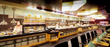 A buffet setup with multiple food stations and a chef preparing food.
