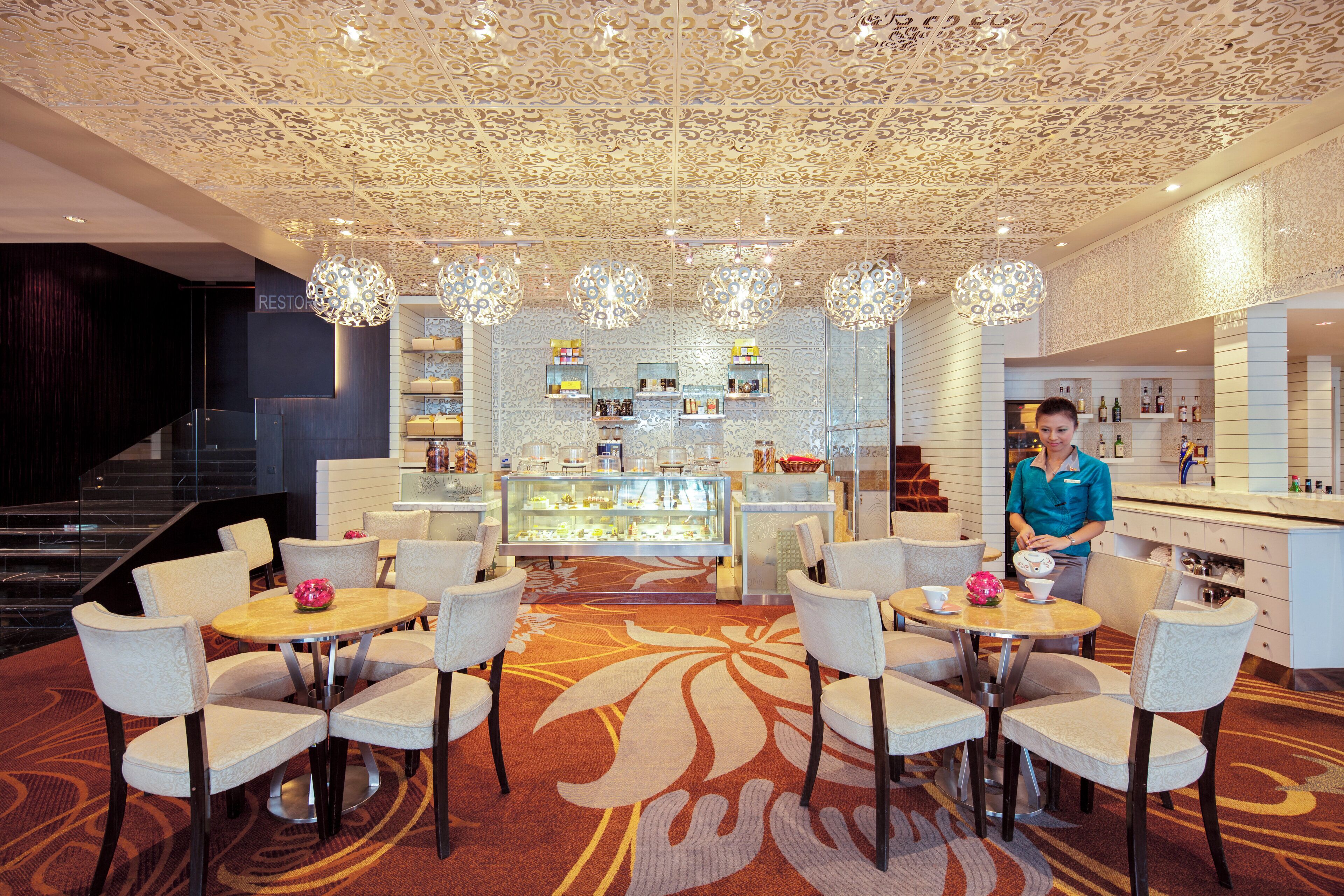 Un hall de hotel con un área de estar central, un bar y una vitrina con objetos.