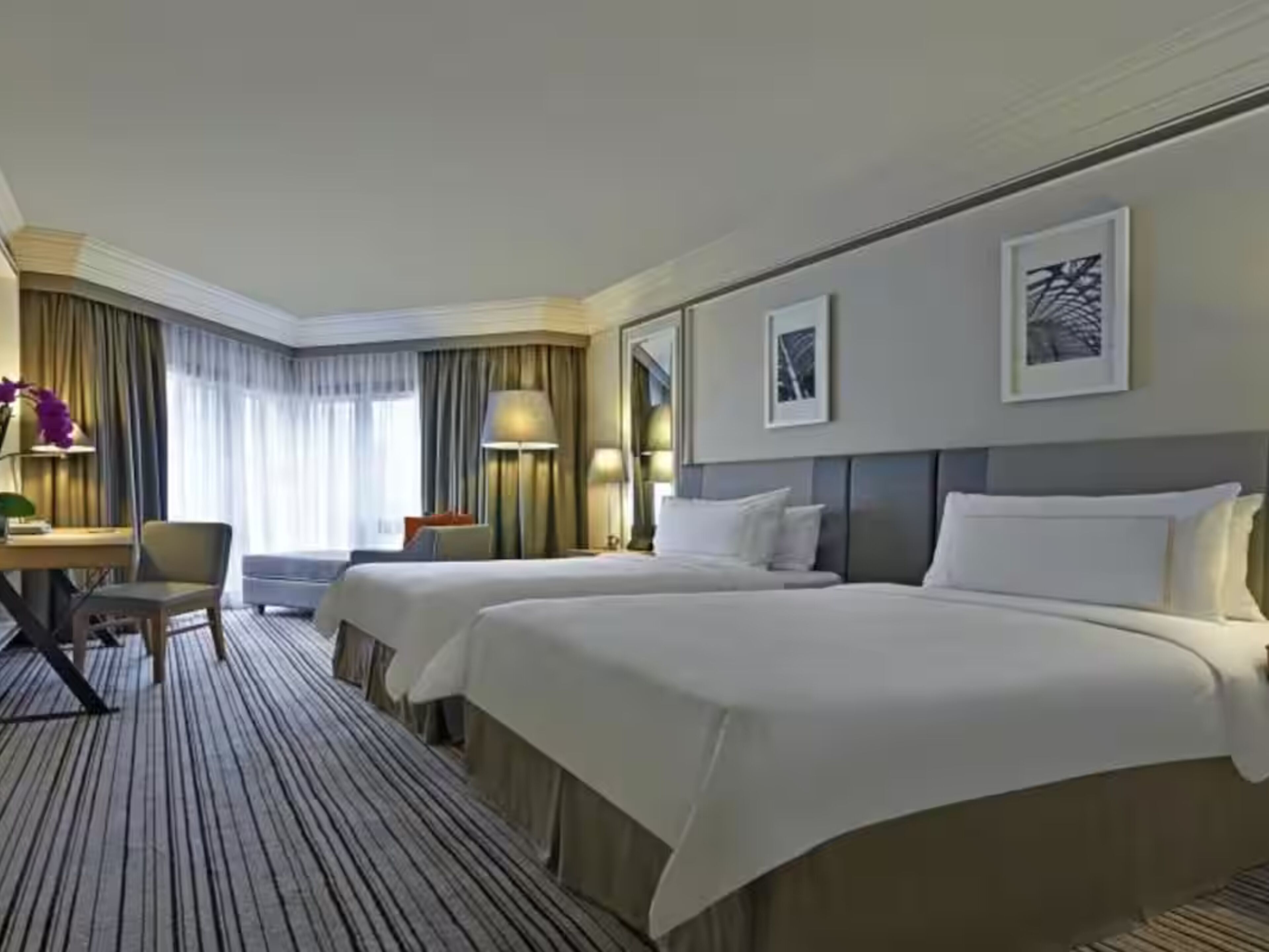 Una habitación de hotel con dos camas, un escritorio, una silla y una lámpara.