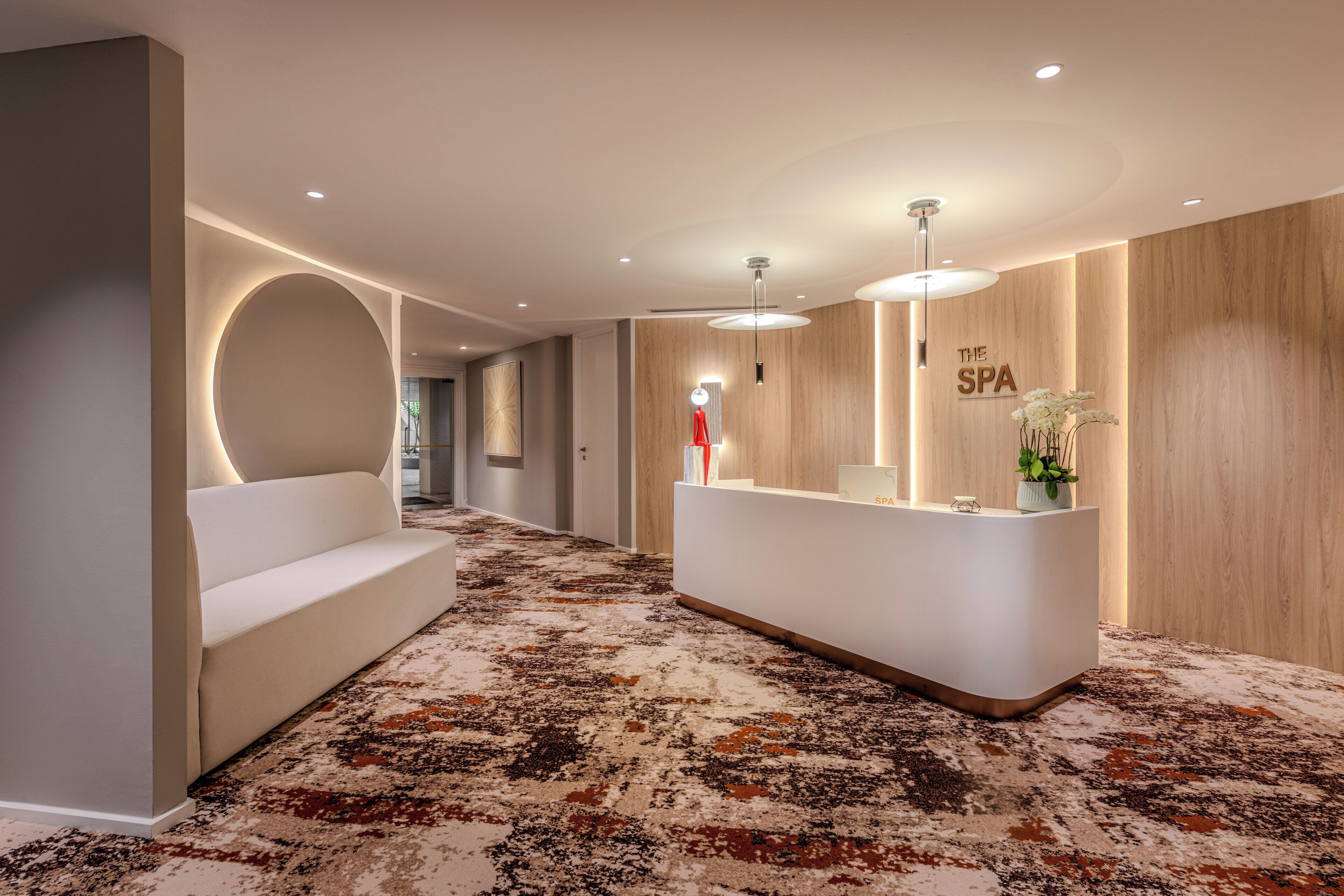 Un espace d’accueil moderne comprenant un comptoir de réception, un coin salon et un panneau indiquant la présence d’un spa.