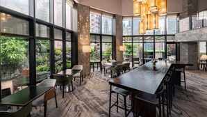 A modern hotel lobby with large windows, a long reception table, and a patterned carpet.