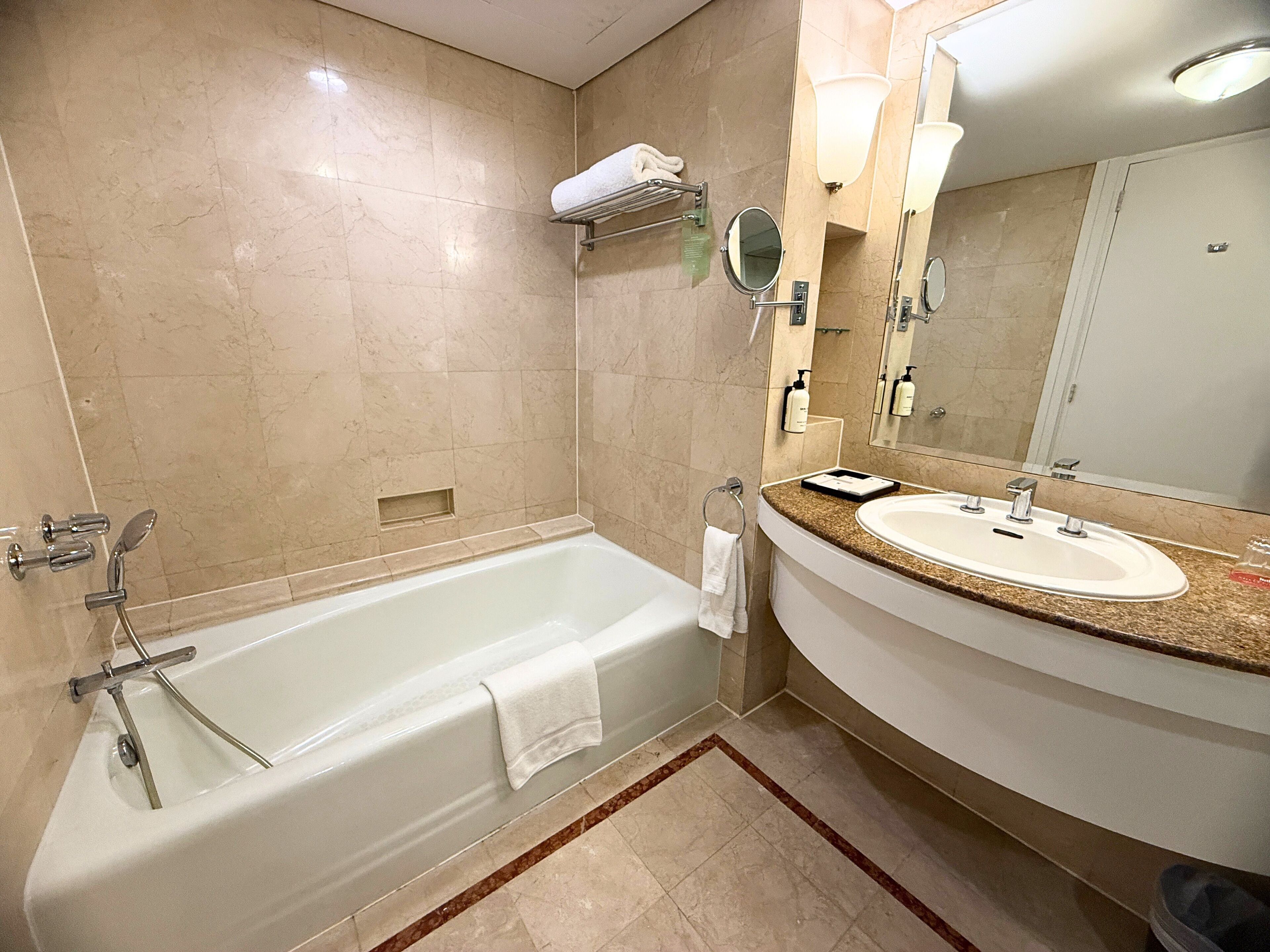 Un baño moderno con una bañera, un lavabo y un espejo grande.