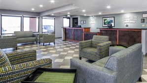 A hotel lobby with patterned armchairs, a reception desk, and framed artwork on the walls.