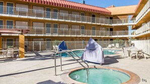 A hotel with a pool area, including a hot tub and lounge chairs.