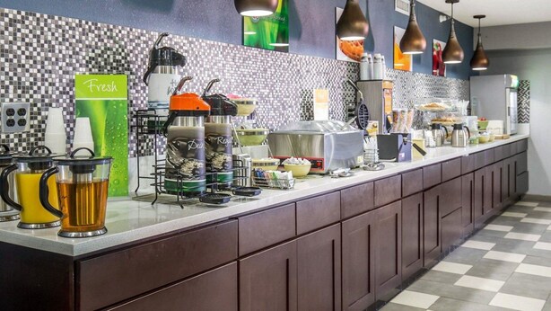 A long counter with various food and drink dispensers, a coffee maker, and a microwave.