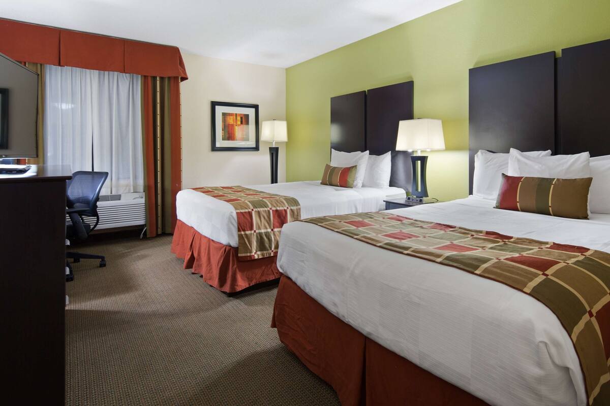Ein Hotelzimmer mit zwei Betten, einem Schreibtisch und einem Stuhl.