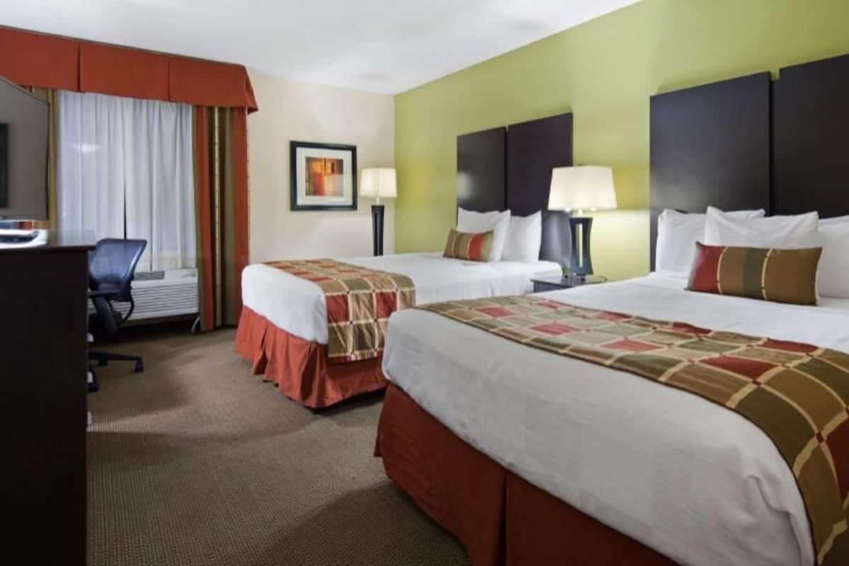 Ein Hotelzimmer mit zwei Betten, einem Schreibtisch und einem Stuhl.