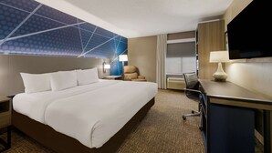 A hotel room with a large bed, a desk with a computer, a TV, and a wall with a geometric pattern. - Comfort Inn Fayetteville I-95 (Fayetteville)