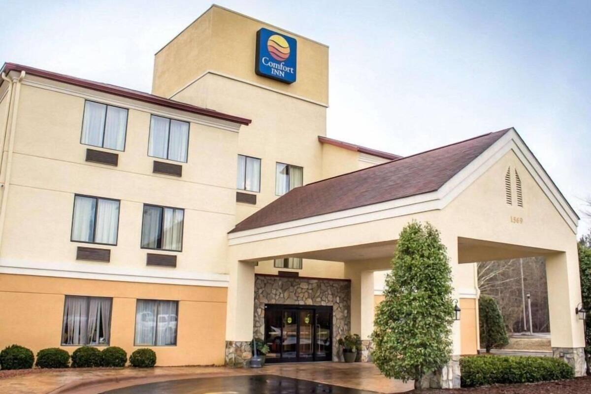 Un hotel Comfort Inn con fachada color crema, entrada de piedra y un pequeño árbol en la parte delantera.